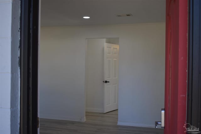 hallway featuring recessed lighting, crown molding, visible vents, baseboards, and wood finished floors