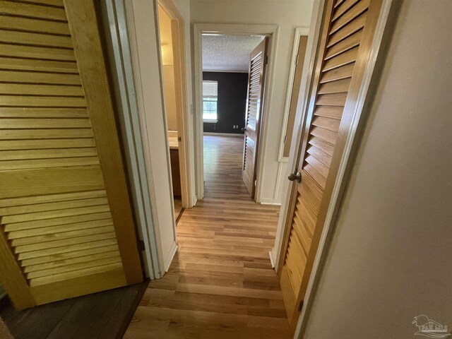 7844 Bay Meadows Dr, Pensacola, FL 32507 - hall with light wood-style flooring, baseboards, and a textured ceiling