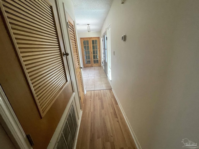 7844 Bay Meadows Dr, Pensacola, FL 32507 - corridor with light wood finished floors, french doors, a textured ceiling, visible vents, and baseboards