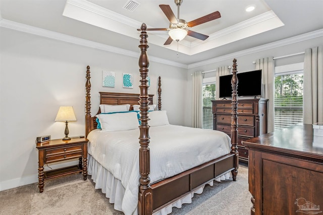 bedroom with ceiling fan, light colored carpet, a tray ceiling, and multiple windows