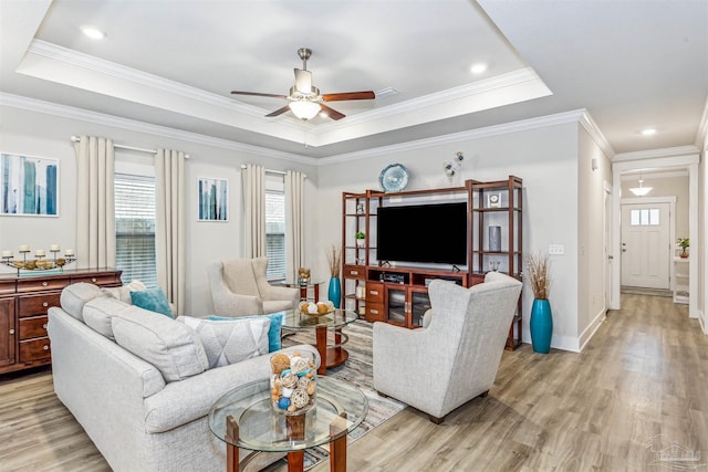 living room featuring a raised ceiling, crown molding, and light hardwood / wood-style floors