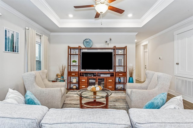 living room featuring a tray ceiling, crown molding, and wood-type flooring