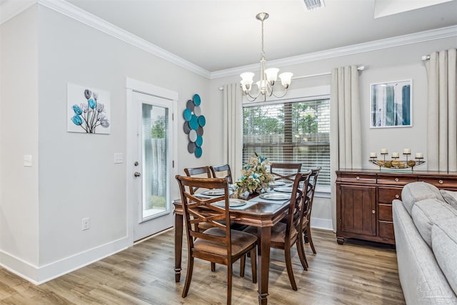 dining space with light hardwood / wood-style flooring, ornamental molding, and a chandelier