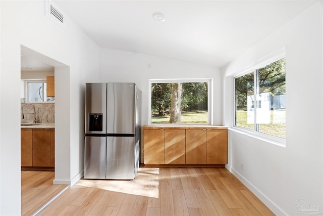 kitchen featuring lofted ceiling, sink, stainless steel fridge, and light hardwood / wood-style flooring