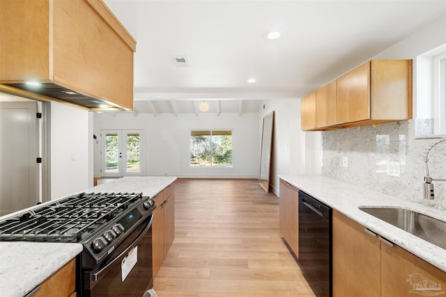 kitchen featuring light stone counters, sink, french doors, and black appliances