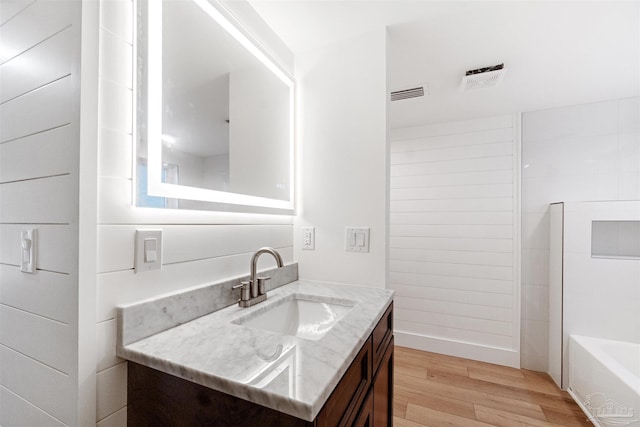 bathroom featuring hardwood / wood-style flooring, vanity, and a bath