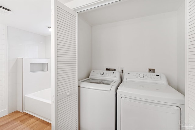 clothes washing area featuring separate washer and dryer and light hardwood / wood-style floors