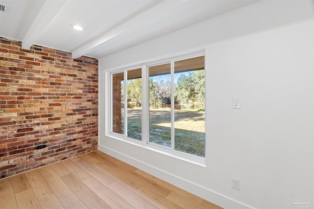 unfurnished room with hardwood / wood-style flooring, beamed ceiling, and brick wall