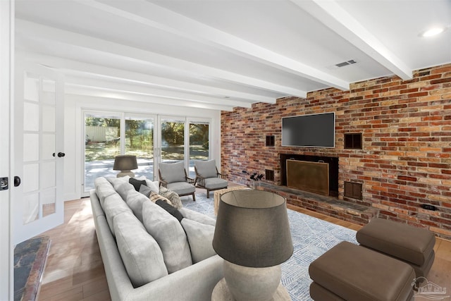 living room with beamed ceiling, brick wall, and a brick fireplace