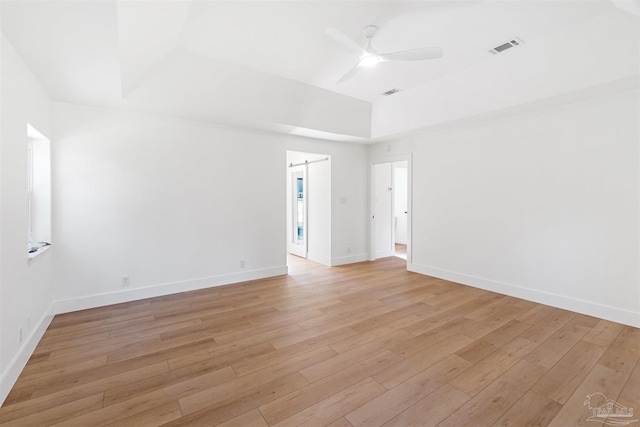 spare room with light hardwood / wood-style flooring, a raised ceiling, and ceiling fan