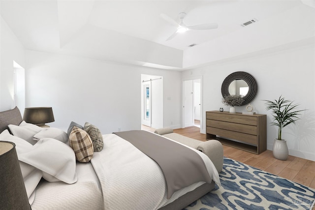 bedroom with a raised ceiling, ceiling fan, and light hardwood / wood-style floors