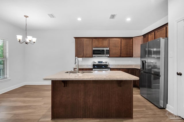 kitchen featuring wood finished floors, a sink, an inviting chandelier, appliances with stainless steel finishes, and visible vents