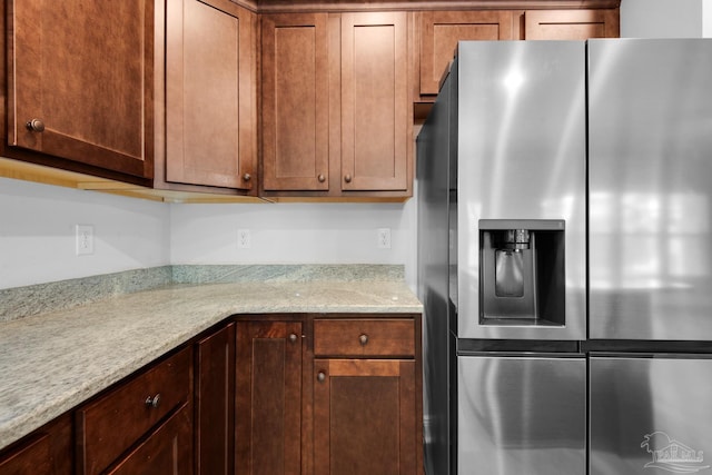 kitchen featuring stainless steel fridge and light stone countertops