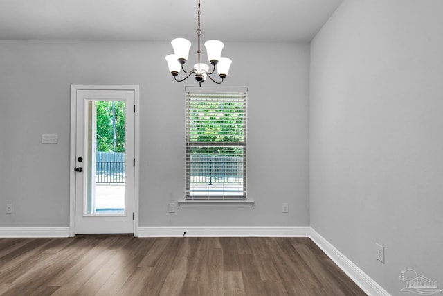interior space featuring dark wood finished floors, baseboards, a notable chandelier, and a healthy amount of sunlight