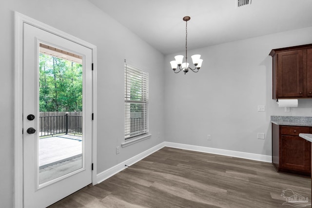 unfurnished dining area featuring an inviting chandelier, dark wood-type flooring, and baseboards