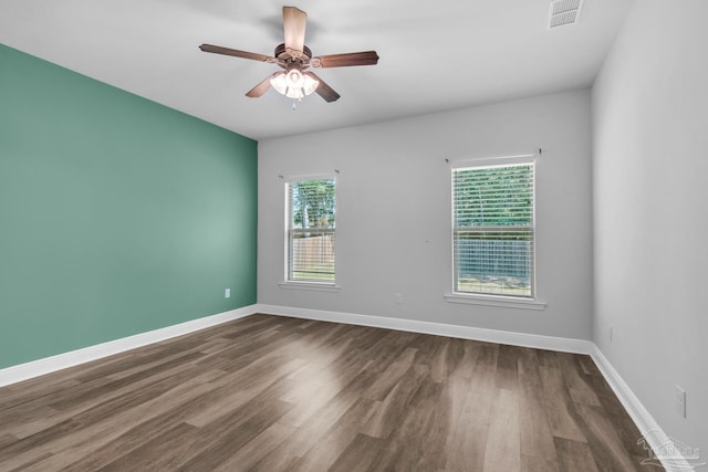 spare room with ceiling fan, baseboards, dark wood-type flooring, and visible vents