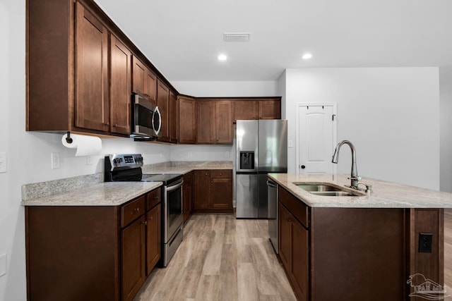 kitchen featuring a sink, a center island with sink, light wood-style flooring, appliances with stainless steel finishes, and visible vents