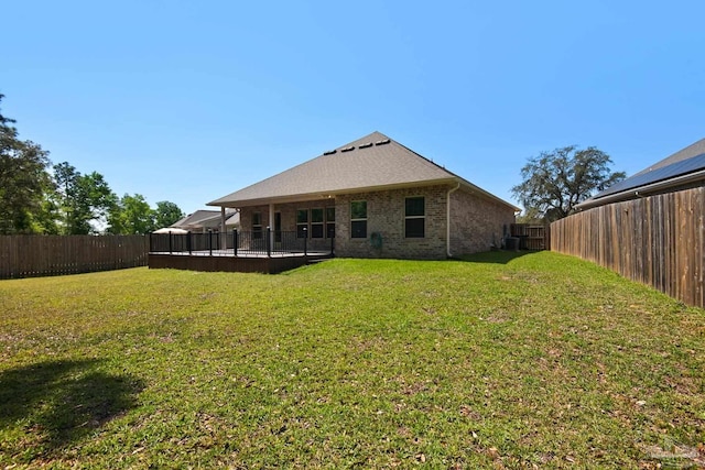 rear view of property with a fenced backyard, brick siding, and a yard