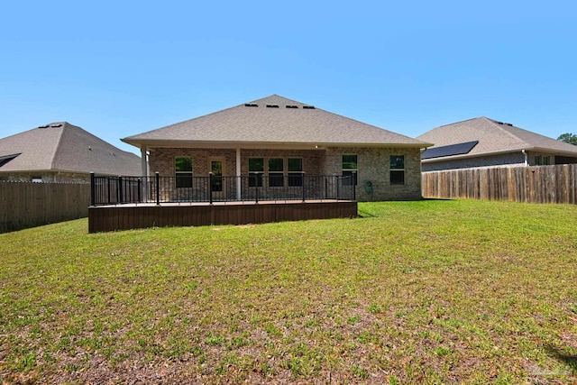 rear view of house featuring a fenced backyard, brick siding, and a yard