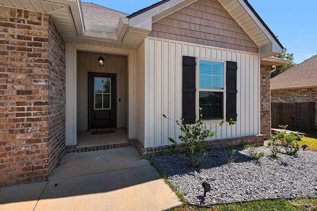 doorway to property with board and batten siding and fence