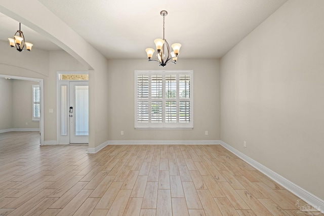 12789 Island Spirit Dr, Pensacola, FL 32506 - spare room with arched walkways, light wood-style floors, baseboards, and an inviting chandelier