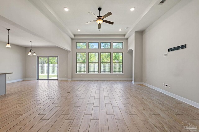 12789 Island Spirit Dr, Pensacola, FL 32506 - unfurnished living room with arched walkways, baseboards, light wood finished floors, and ceiling fan with notable chandelier