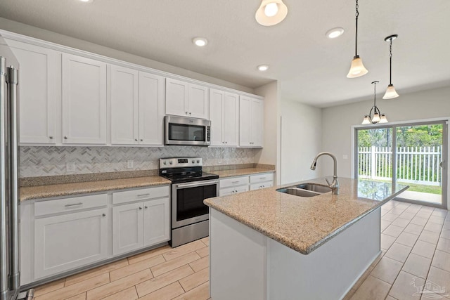 12789 Island Spirit Dr, Pensacola, FL 32506 - kitchen with a sink, white cabinets, an island with sink, backsplash, and appliances with stainless steel finishes