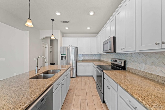 12789 Island Spirit Dr, Pensacola, FL 32506 - kitchen featuring stainless steel appliances, arched walkways, a sink, and white cabinetry