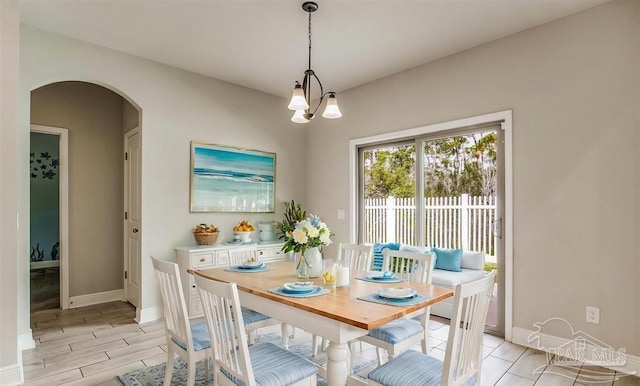 12789 Island Spirit Dr, Pensacola, FL 32506 - dining room featuring arched walkways, wood finish floors, an inviting chandelier, and baseboards