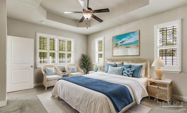 12789 Island Spirit Dr, Pensacola, FL 32506 - carpeted bedroom with multiple windows, a ceiling fan, baseboards, and a tray ceiling