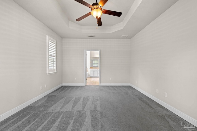 12789 Island Spirit Dr, Pensacola, FL 32506 - spare room featuring a tray ceiling, dark colored carpet, visible vents, baseboards, and ceiling fan
