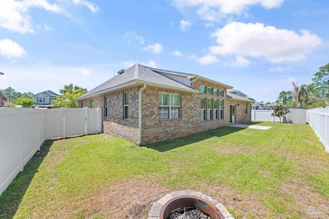 12789 Island Spirit Dr, Pensacola, FL 32506 - back of house with brick siding, a lawn, a fenced backyard, and an outdoor fire pit