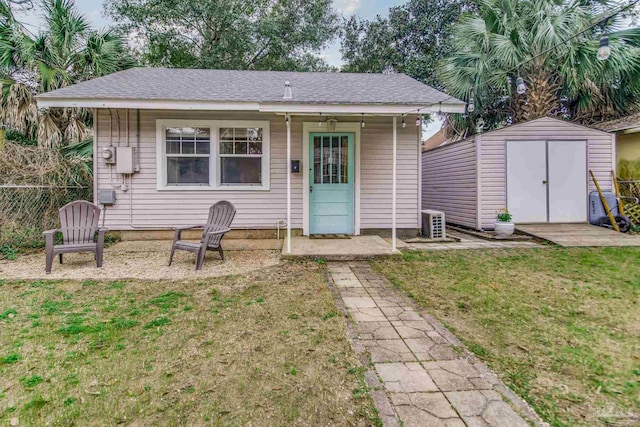 view of front facade featuring a storage shed, a front yard, fence, and an outdoor structure