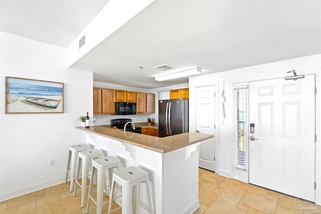 kitchen with a breakfast bar, sink, kitchen peninsula, and black appliances