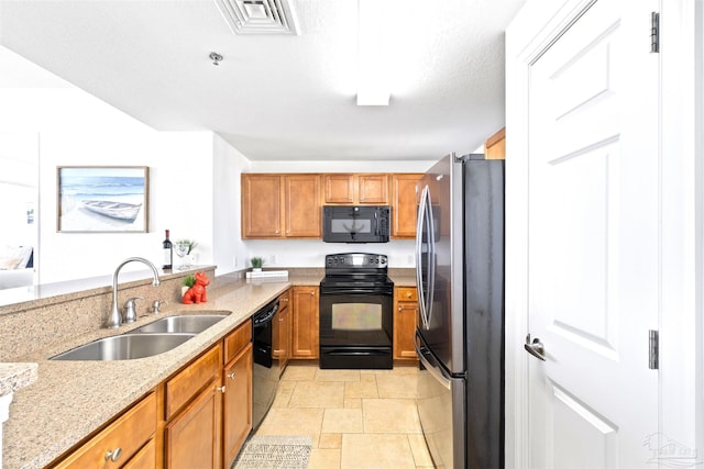 kitchen with light stone counters, sink, black appliances, and a textured ceiling