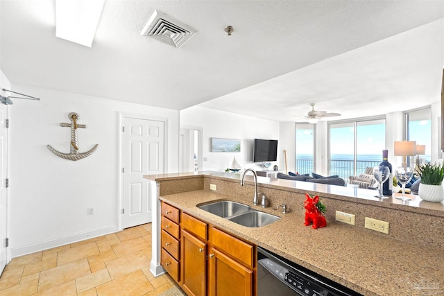 kitchen with stainless steel dishwasher, ceiling fan, light stone counters, and sink