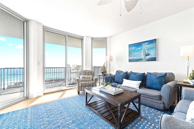 tiled living room with floor to ceiling windows, ceiling fan, and a water view