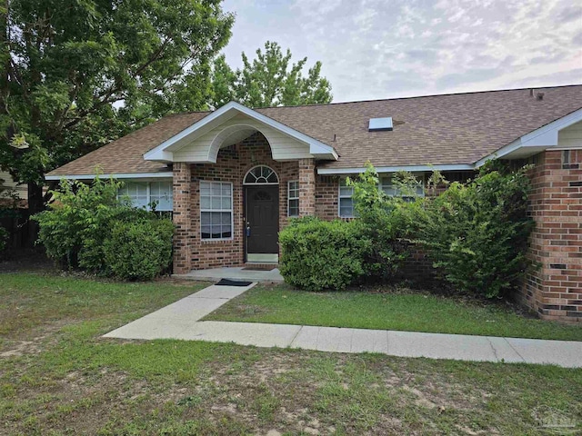 view of front of house with a front lawn, brick siding, and roof with shingles