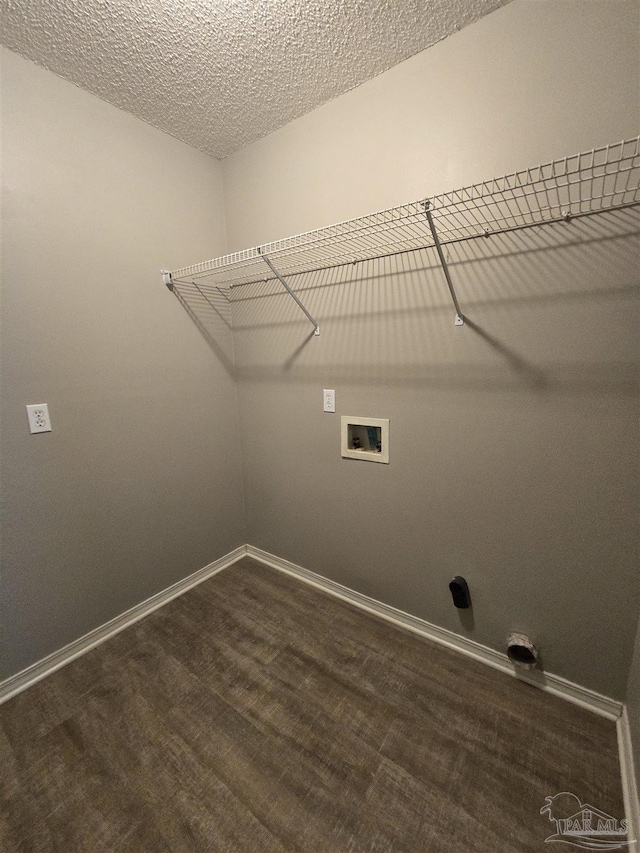 clothes washing area with laundry area, a textured ceiling, dark wood finished floors, washer hookup, and baseboards