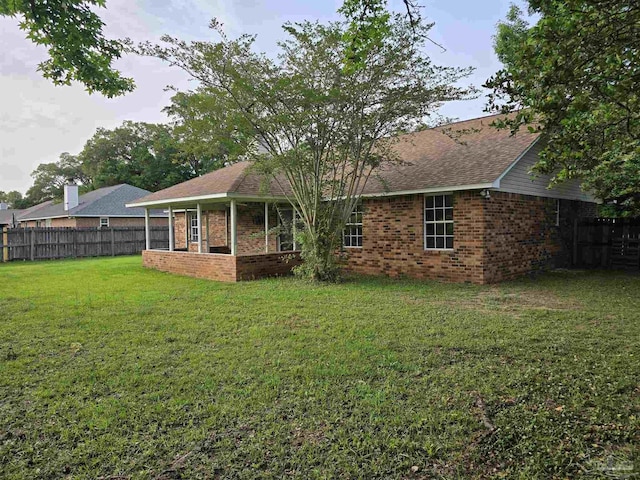 back of property with brick siding, fence, and a lawn
