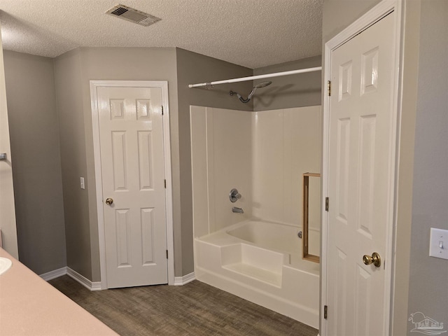 full bathroom featuring a textured ceiling, visible vents, wood finished floors, and shower / bathtub combination