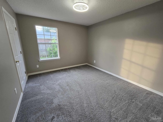 unfurnished room with baseboards, dark carpet, and a textured ceiling