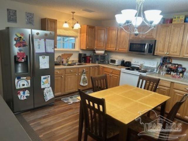 8714 Figland Ave, Pensacola, FL 32534 - kitchen with a chandelier, stainless steel appliances, light countertops, and dark wood-style flooring