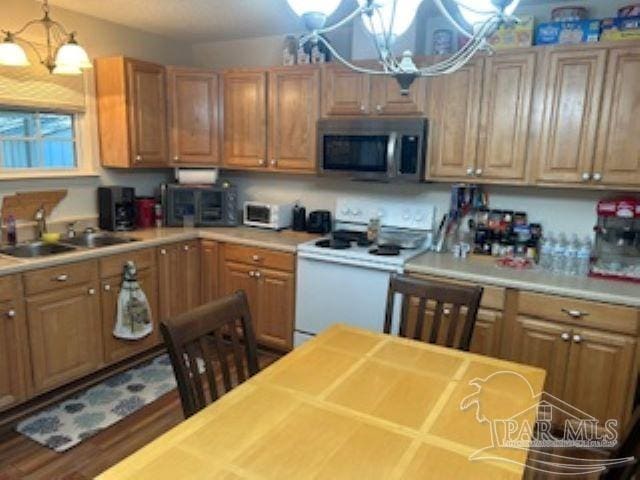 8714 Figland Ave, Pensacola, FL 32534 - kitchen featuring white electric stove, a sink, light countertops, stainless steel microwave, and a notable chandelier