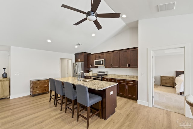 kitchen with stainless steel appliances, a sink, a ceiling fan, a breakfast bar area, and an island with sink