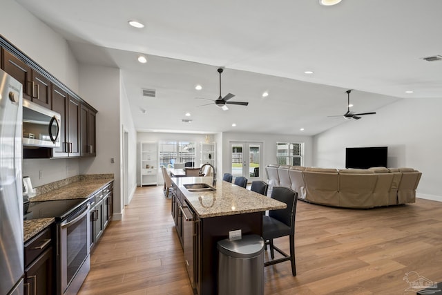 kitchen featuring stainless steel appliances, ceiling fan, a sink, a breakfast bar area, and vaulted ceiling