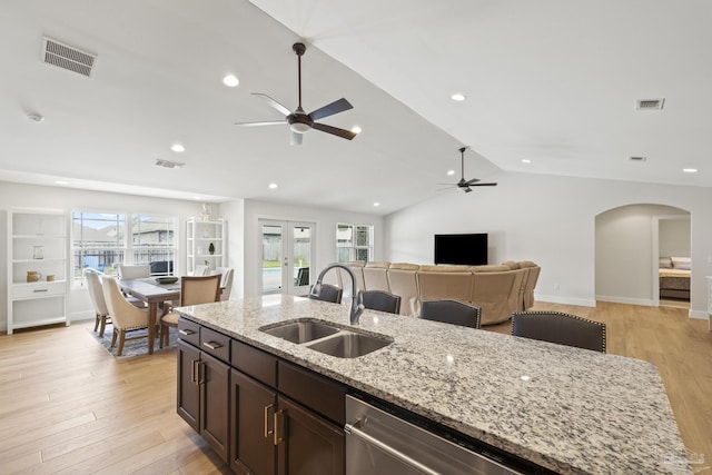kitchen with a sink, a ceiling fan, arched walkways, open floor plan, and light wood-style floors