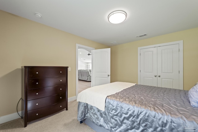 bedroom with light carpet, baseboards, and a closet