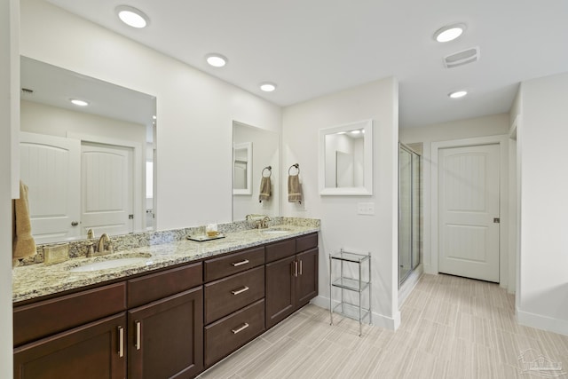 full bathroom with baseboards, a shower stall, and double vanity