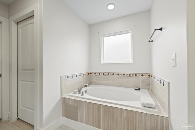 bathroom with a garden tub and baseboards
